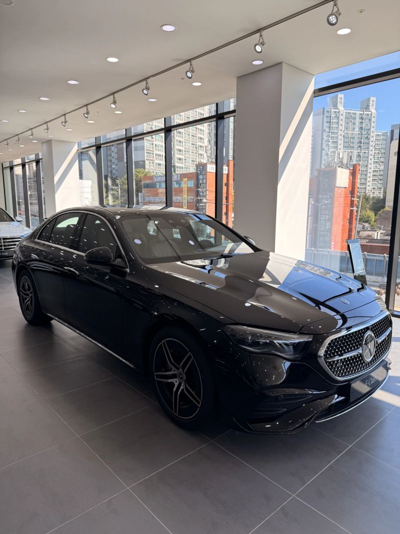 전시장 창가에 놓인 블랙 E300 4MATIC AMG Line을 앞 3/4 측면에서 본 모습