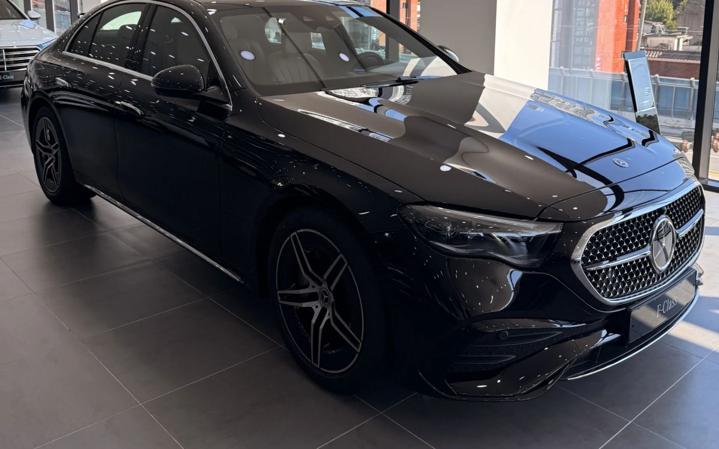 의정부 전시장 창가에 전시된 블랙 벤츠 E300 4MATIC AMG Line, 앞 3/4 측면에서 본 실차 사진
